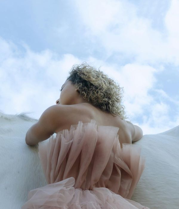 Woman in a calm, flowing pose against a serene background.
